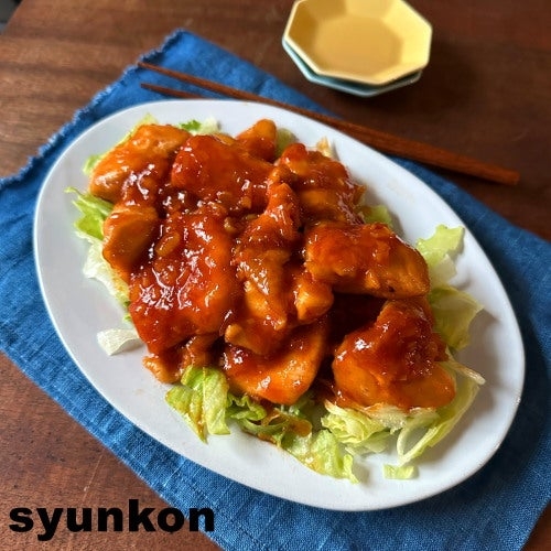 皿に盛られたレタスの上にソースがかかった鶏肉料理が置かれている。横に箸が見える。