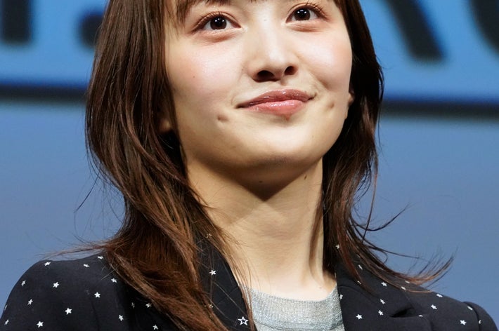 女性が星柄のジャケットを着てステージに立っている。