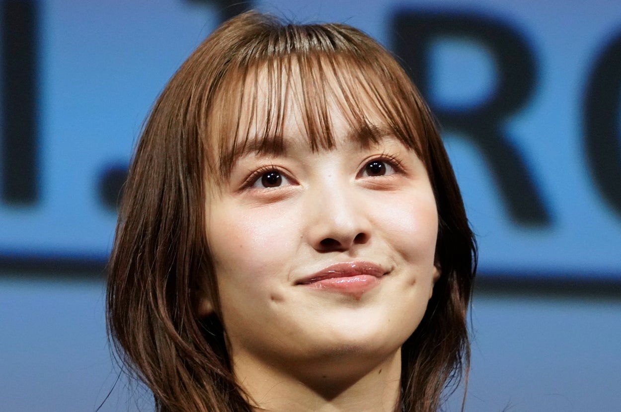 女性が星柄のジャケットを着てステージに立っている。
