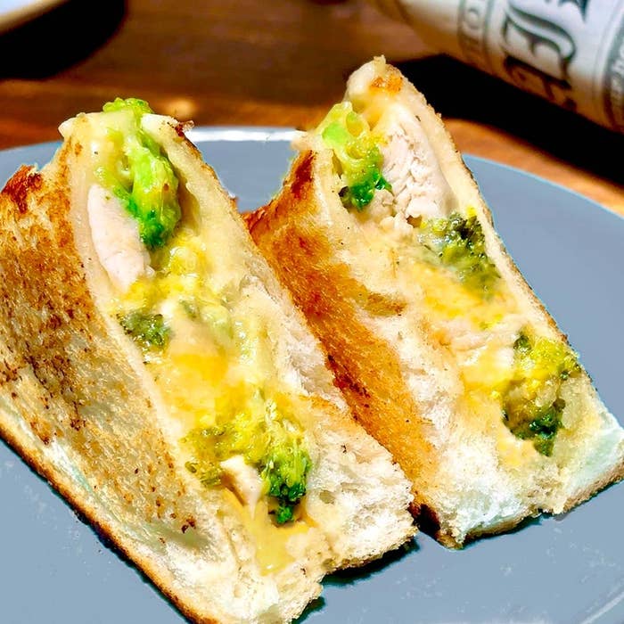 トーストサンドイッチの断面。チキン、ブロッコリー、チーズが挟まれ、皿に盛られている。