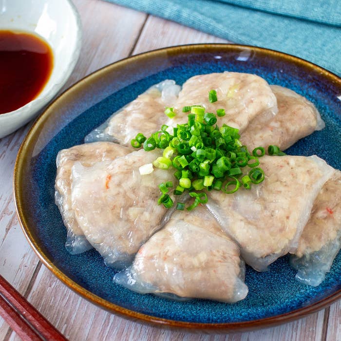 皿に盛り付けられた数個の魚のすり身の蒸し物が、刻みネギとともに並んでいます。ソースの皿が添えられています。