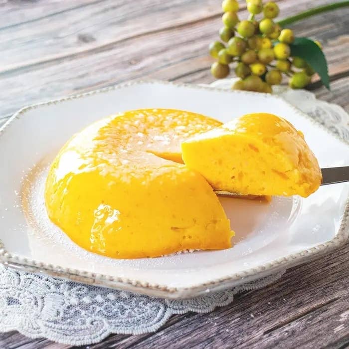 デザートプレートにある滑らかなクリーム色の洋菓子。一个切り分けられた一部がナイフで持ち上げられている。