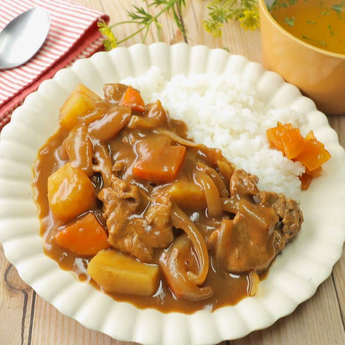カレーライスのプレート。ご飯の隣にじゃがいも、にんじん、牛肉入りのカレーが盛り付けられている。