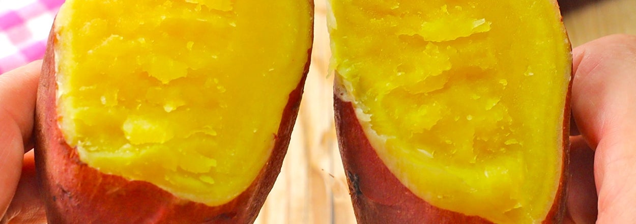 手に持った焼き芋が半分に割られ、中の柔らかい部分が見える。
