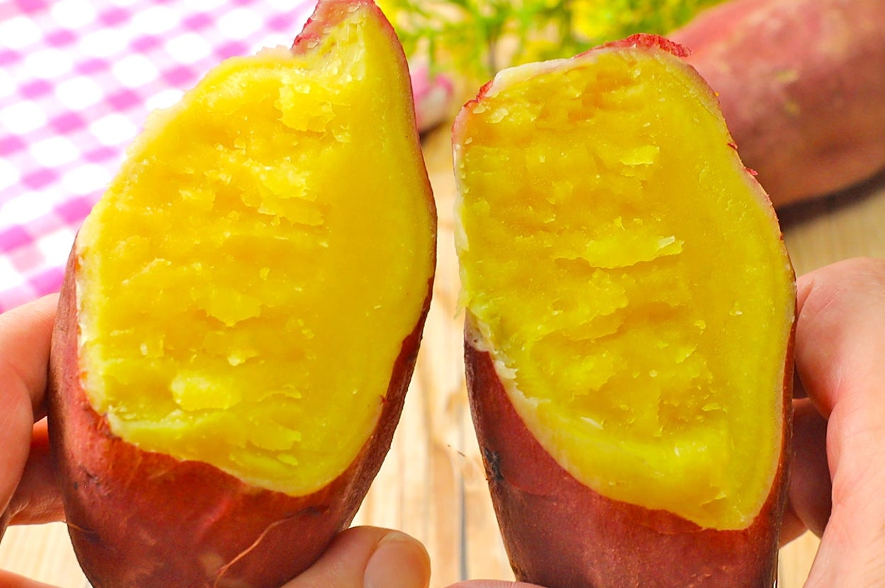 手に持った焼き芋が半分に割られ、中の柔らかい部分が見える。