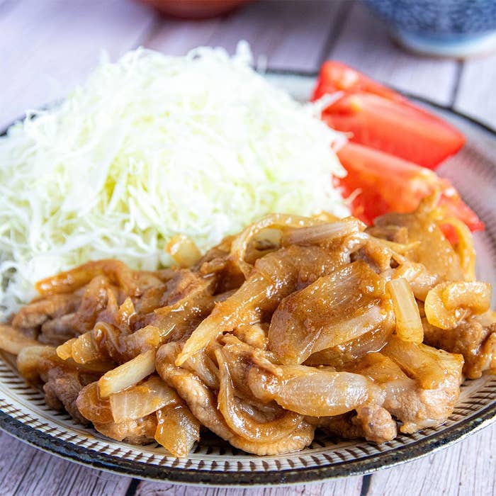 キャベツの千切りとトマトを添えた、玉ねぎと肉の料理の盛り付け。