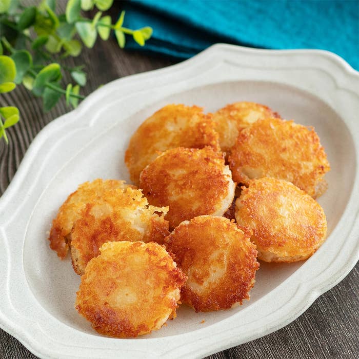 白い皿に盛られた丸い揚げ物の料理。植物の装飾が側にある。