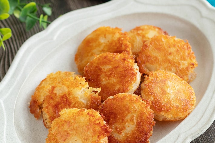 お皿に盛られたカリカリに焼かれたポテトのコイン状の料理。横には緑の飾り。