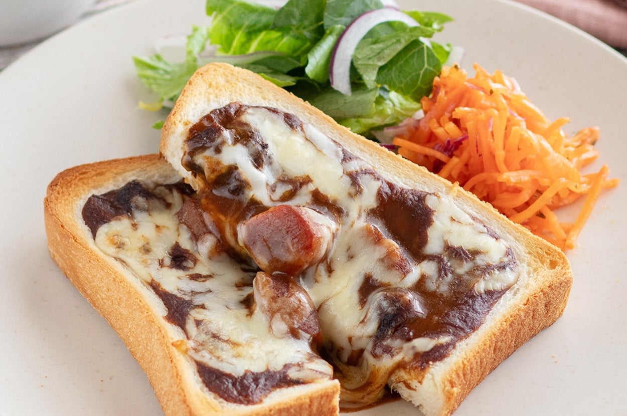 トーストにカレーとチーズがのり、横にサラダと細切りニンジンがある料理の写真。