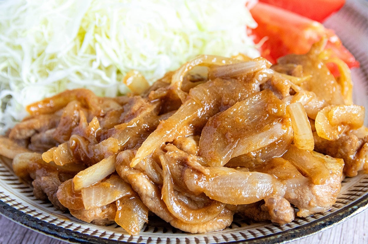 キャベツの千切りとトマト、玉ねぎ入りの豚肉炒めが盛り付けられた、おいしそうな料理の写真。