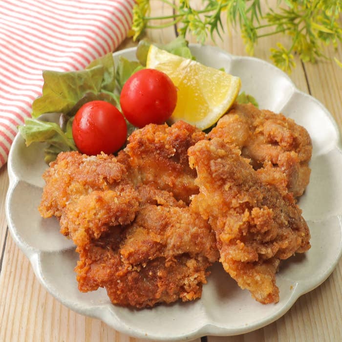 鶏の唐揚げが皿に盛られ、レタス、ミニトマト、レモンが添えられている。