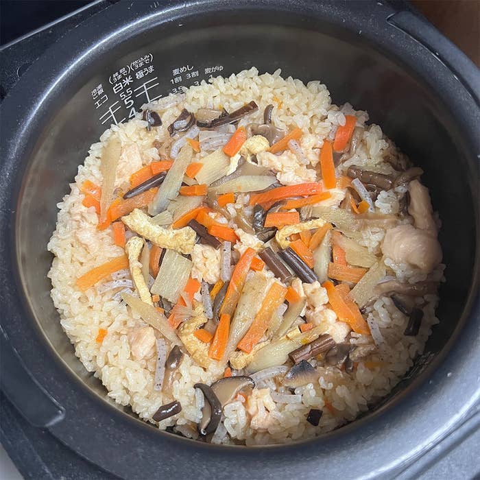炊飯器の中で調理された炊き込みご飯。きのこ、人参、鶏肉が混ざっている。