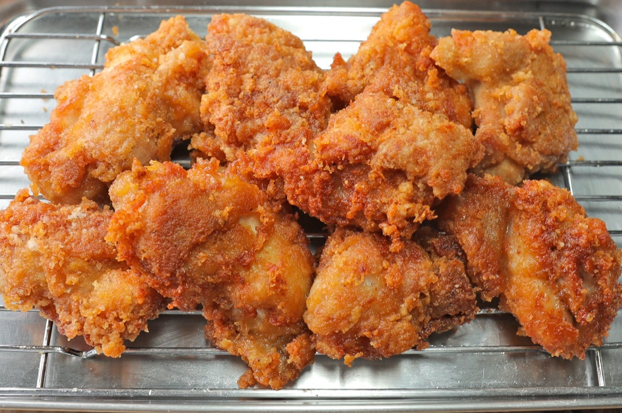 揚げ物が網の上に乗っている。背景にサラダのボウルが置かれている。