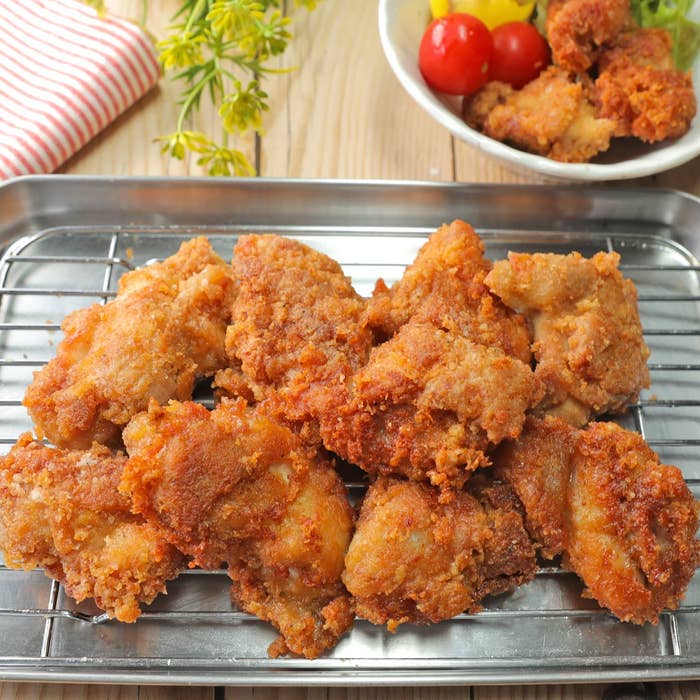 揚げ物が網の上に乗っている。背景にサラダのボウルが置かれている。