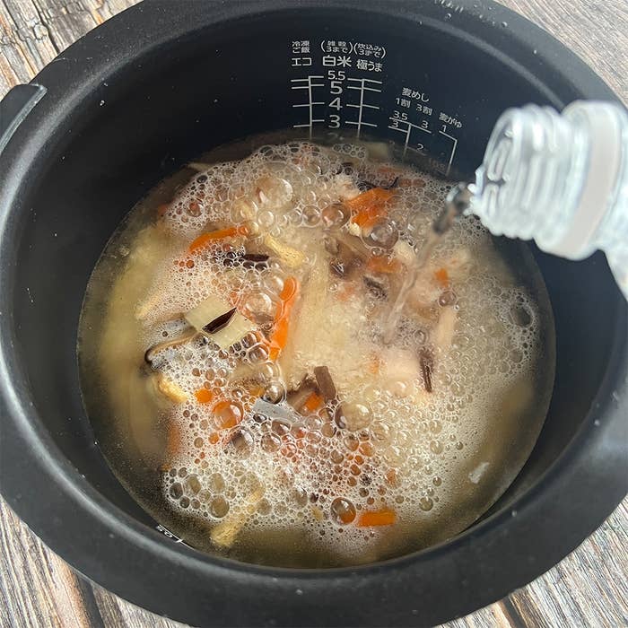 炊飯器に入ったご飯に、具材と炭酸水が加えられて炊かれる様子。