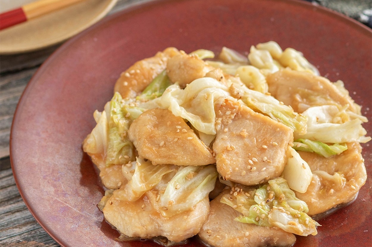 鶏肉とキャベツの炒め物が皿に盛られている。ゴマがトッピングされ、食欲をそそる見た目。