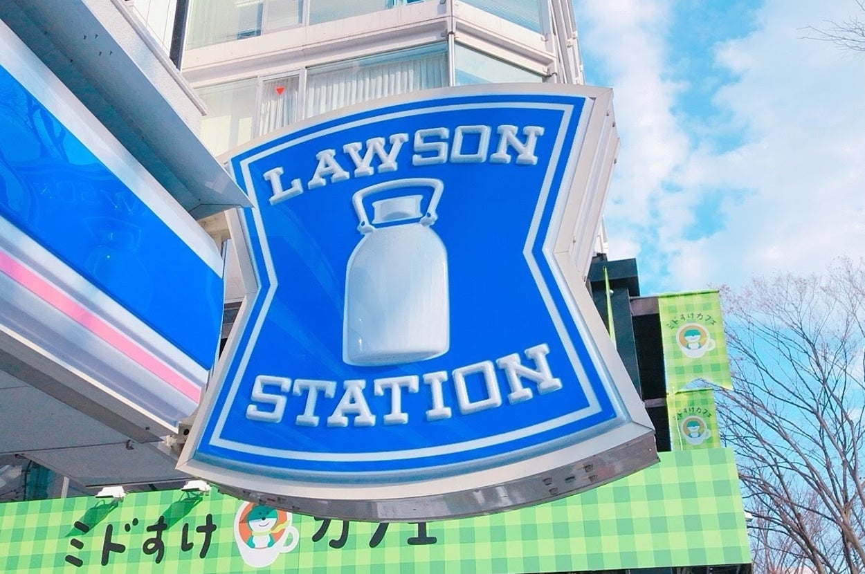 ローソンストアの看板。建物と木々が背景。