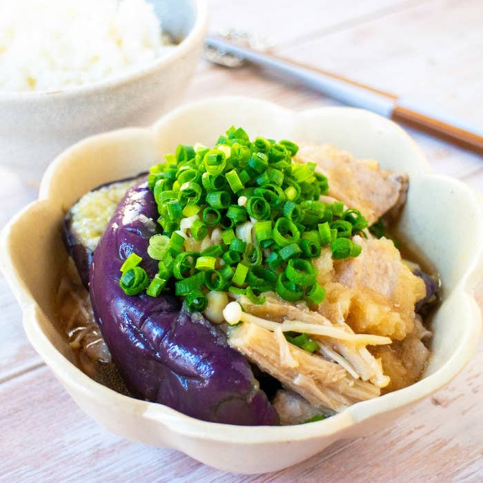 日本の焼きナスとブタ肉の料理、刻みネギがトッピングされ、ご飯と共に提供されています。