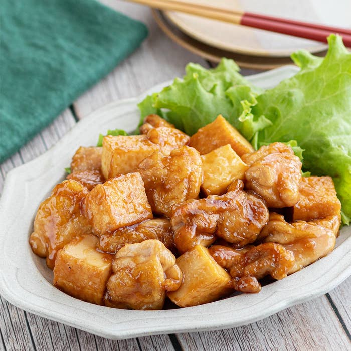 皿に盛られた鶏肉と豆腐の炒め物。背景に箸とナプキンが見える。