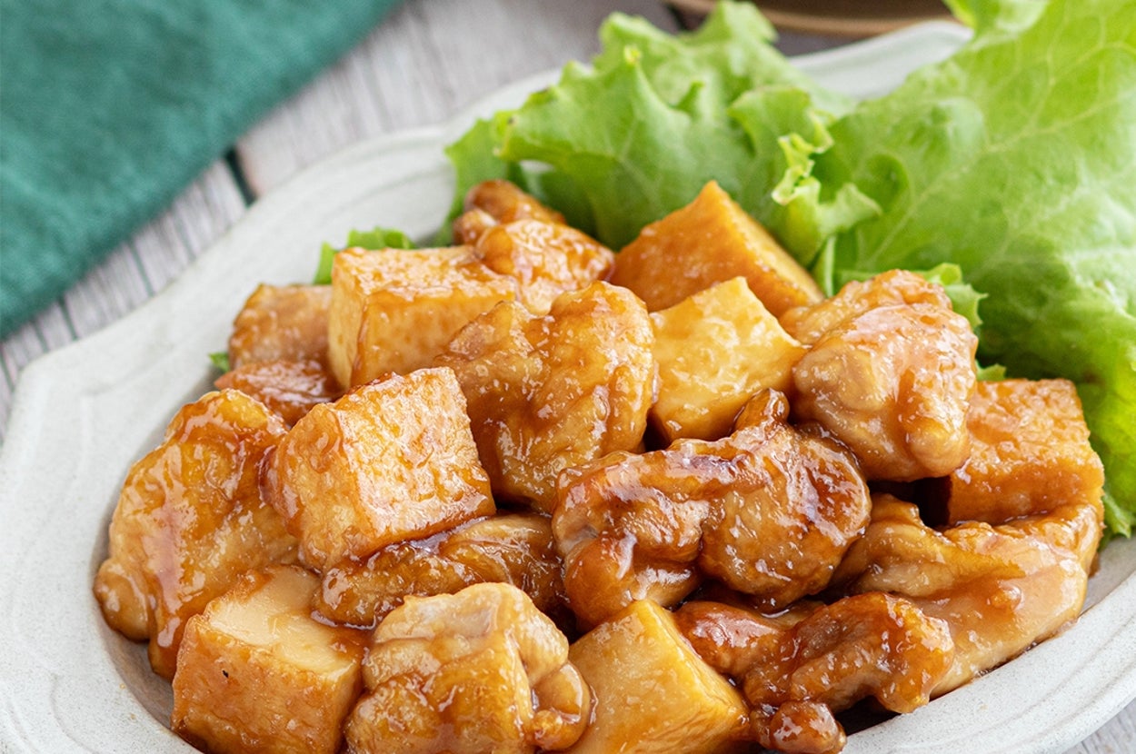豆腐と鶏肉の炒め物が白い皿に盛られ、レタスが添えられている。
