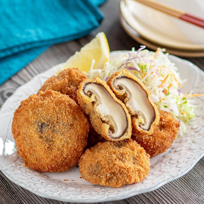 パン粉をまぶした揚げキノコが皿に盛られている。横には千切りキャベツとレモンが添えられている。