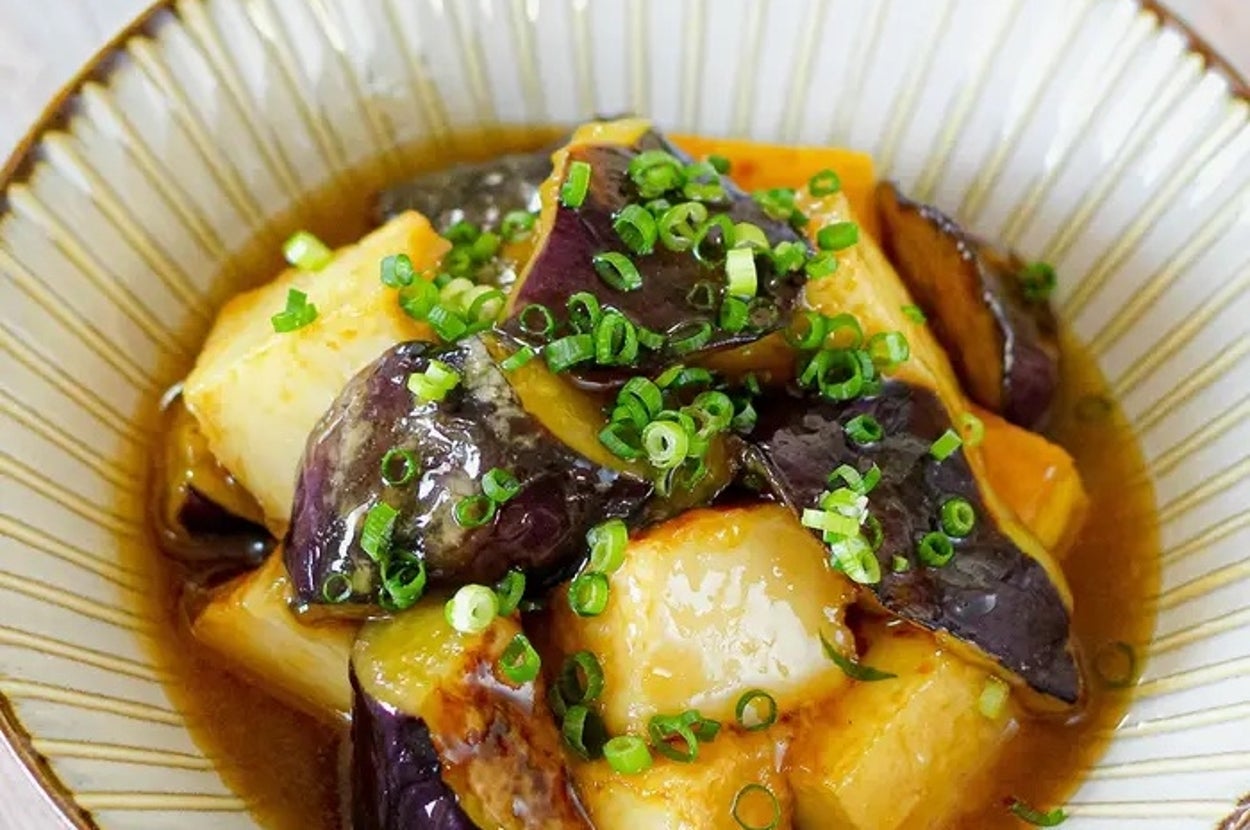 ネギが載ったナスと豆腐の煮物が器に盛られている料理。