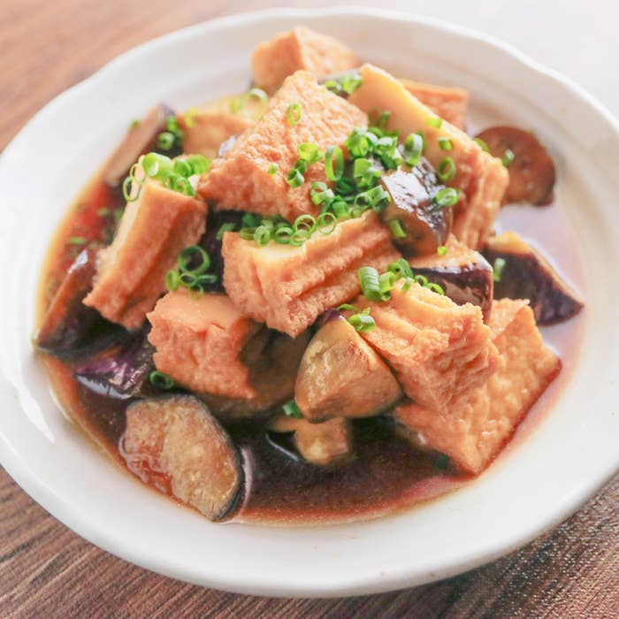 厚揚げとなすの料理。白い皿に盛られ、刻みネギが上に散らされています。