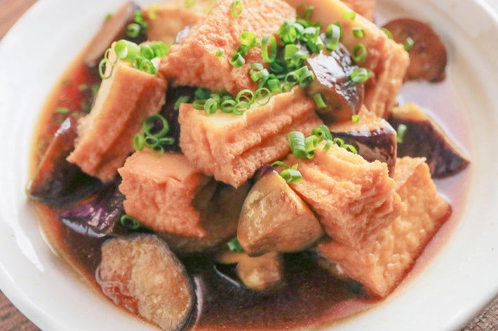 料理は豆腐とナスの煮物で、小口切りのネギがトッピングされています。