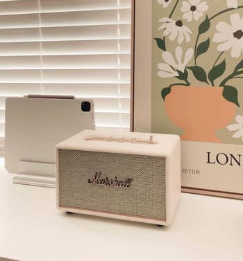 A Marshall talker connected a achromatic table beside a tablet connected a basal and a poster with floral design