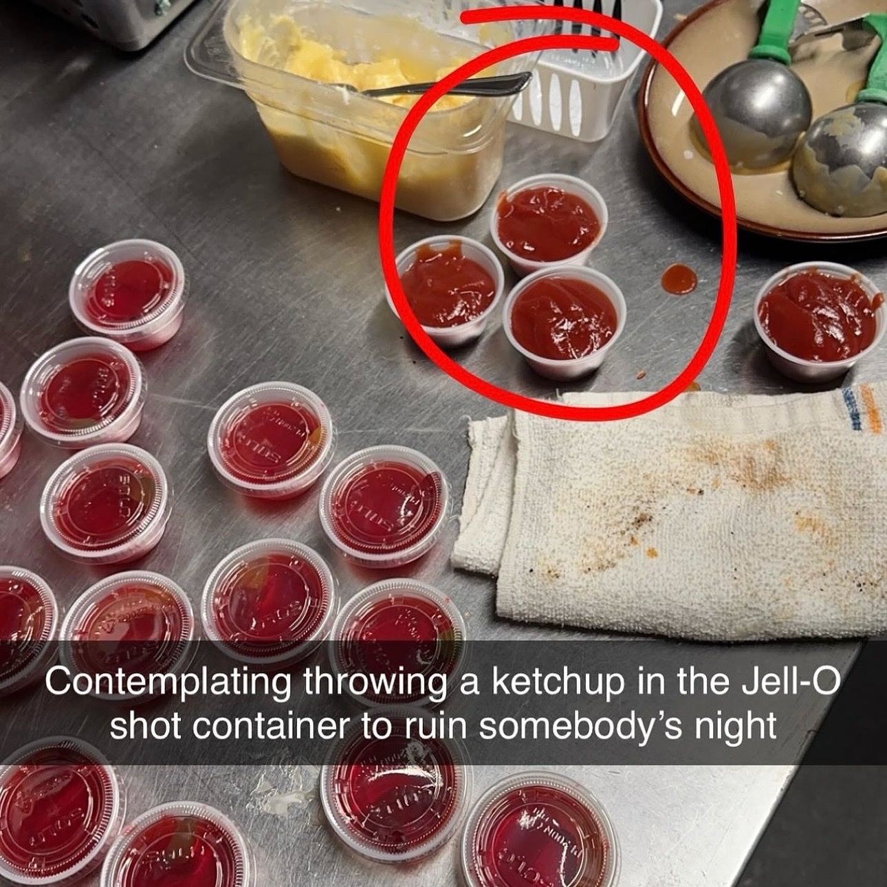 Plastic cups filled with a red substance labeled as Jell-O shots are shown. A circle highlights ketchup nearby. A towel rests beside the cups