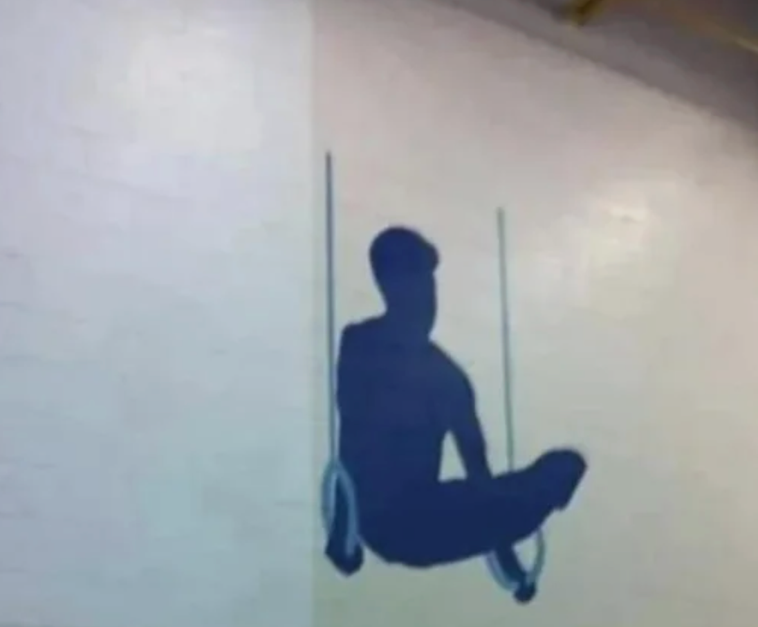 Optical illusion wall art showing a silhouette of a person sitting on gymnastic rings, appearing like a real figure when viewed from a distance