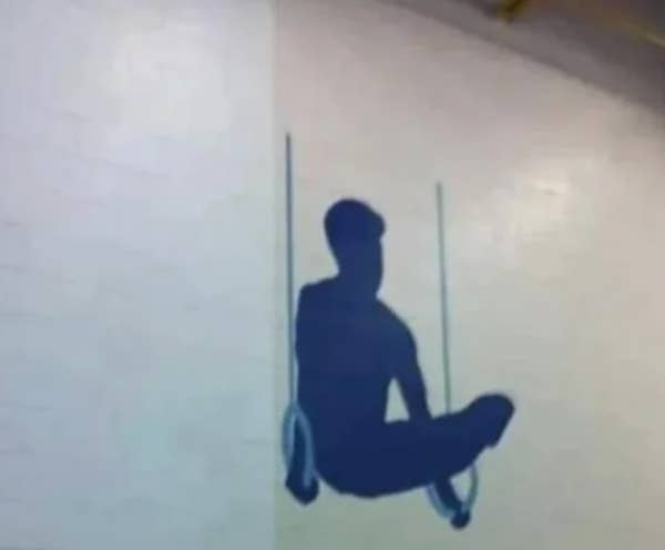 Optical illusion wall art showing a silhouette of a person sitting on gymnastic rings, appearing like a real figure when viewed from a distance