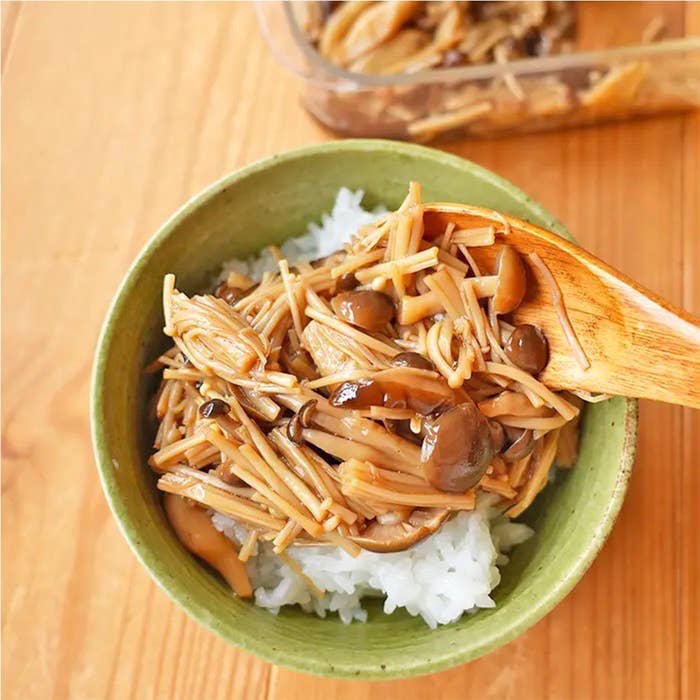 木製スプーンできのこがトッピングされたご飯の入った緑のボウル。