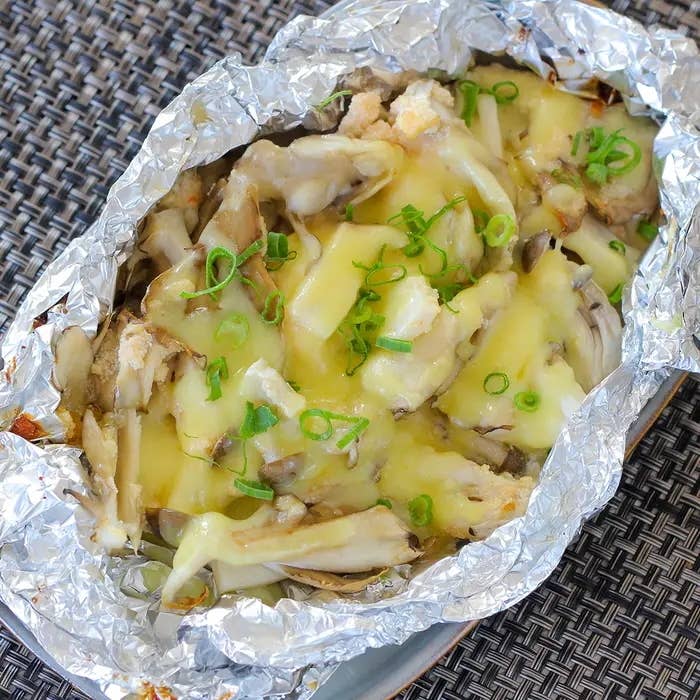 ホイルに包まれたきのこと溶けたチーズの料理。上に刻んだねぎがトッピングされています。