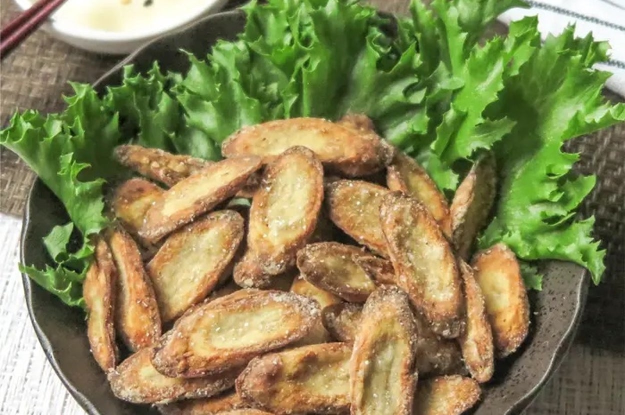 揚げたチップスのような見た目のごぼうの天ぷらがレタスで飾られた器に盛られている。後ろにソースの小皿。