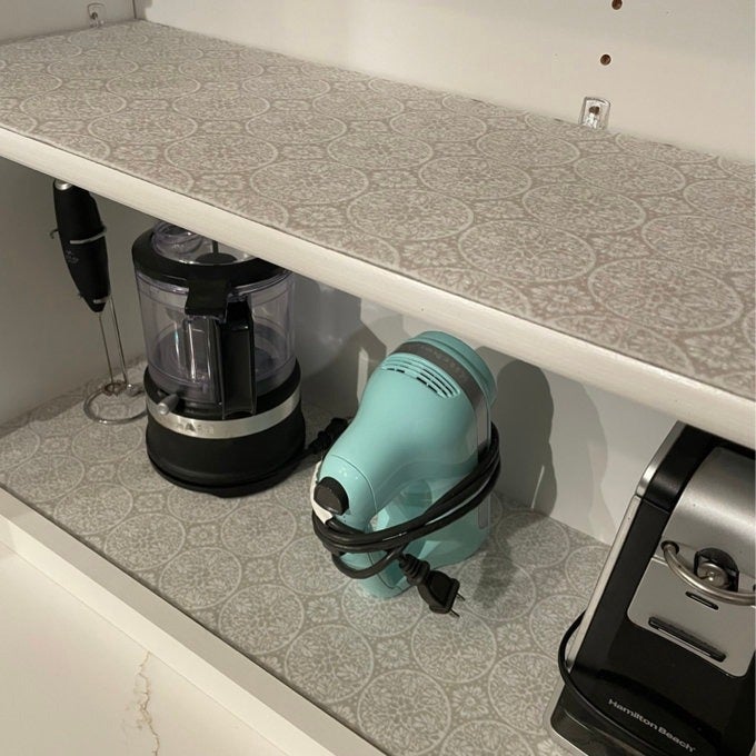 Kitchen shelf with a hand mixer, food processor, immersion blender, and coffee maker, organized for easy access