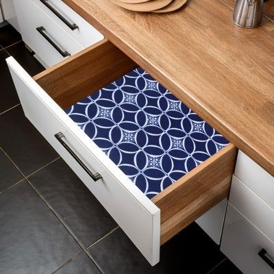 Open kitchen drawer lined with decorative geometric-patterned contact paper