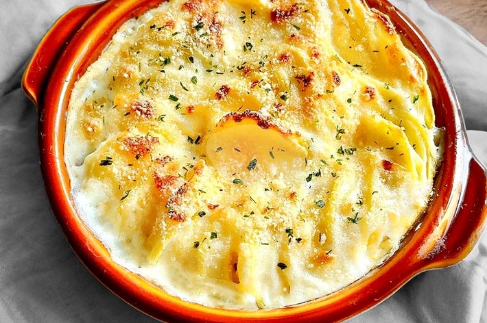 焼きたてのグラタンが器に盛られている。クリーミーなチーズとハーブがトッピングされた食欲をそそる見た目。