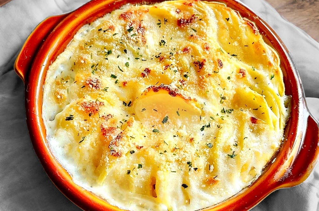 焼きたてのグラタンが器に盛られている。クリーミーなチーズとハーブがトッピングされた食欲をそそる見た目。