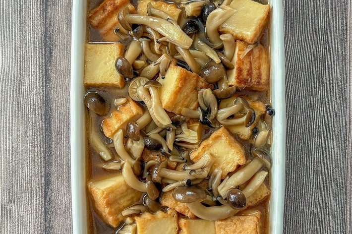 キノコと揚げ豆腐の炒め物が白い皿に盛り付けられた料理。シンプルでヘルシーな一品。