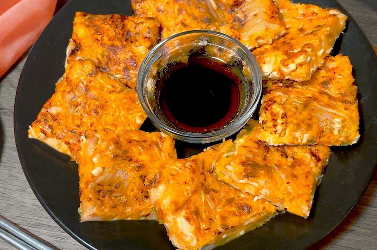 黒い皿に盛られたキムチチヂミの盛り合わせ、中央に醤油ソースの小皿あり。