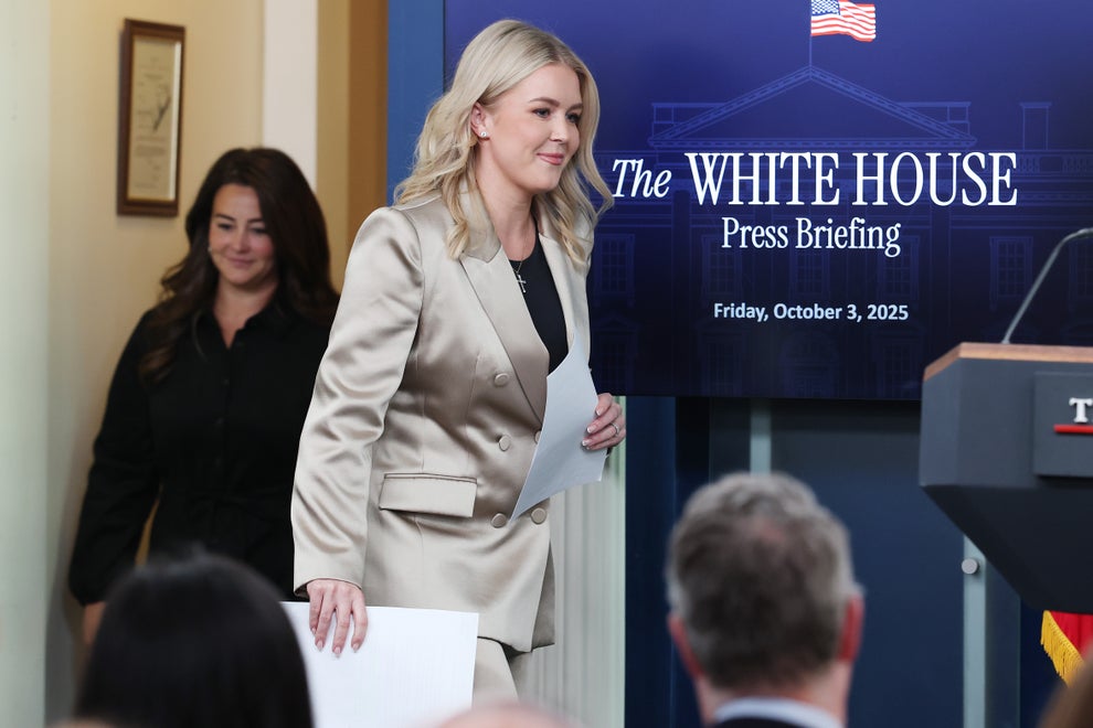 "I've Never Met You": Karoline Leavitt Was Truly Shocked By This Bold Question From The Latinos For Trump Founder 17 A person in a stylish suit walks past a White House press briefing screen, holding papers, followed by another person in black attire