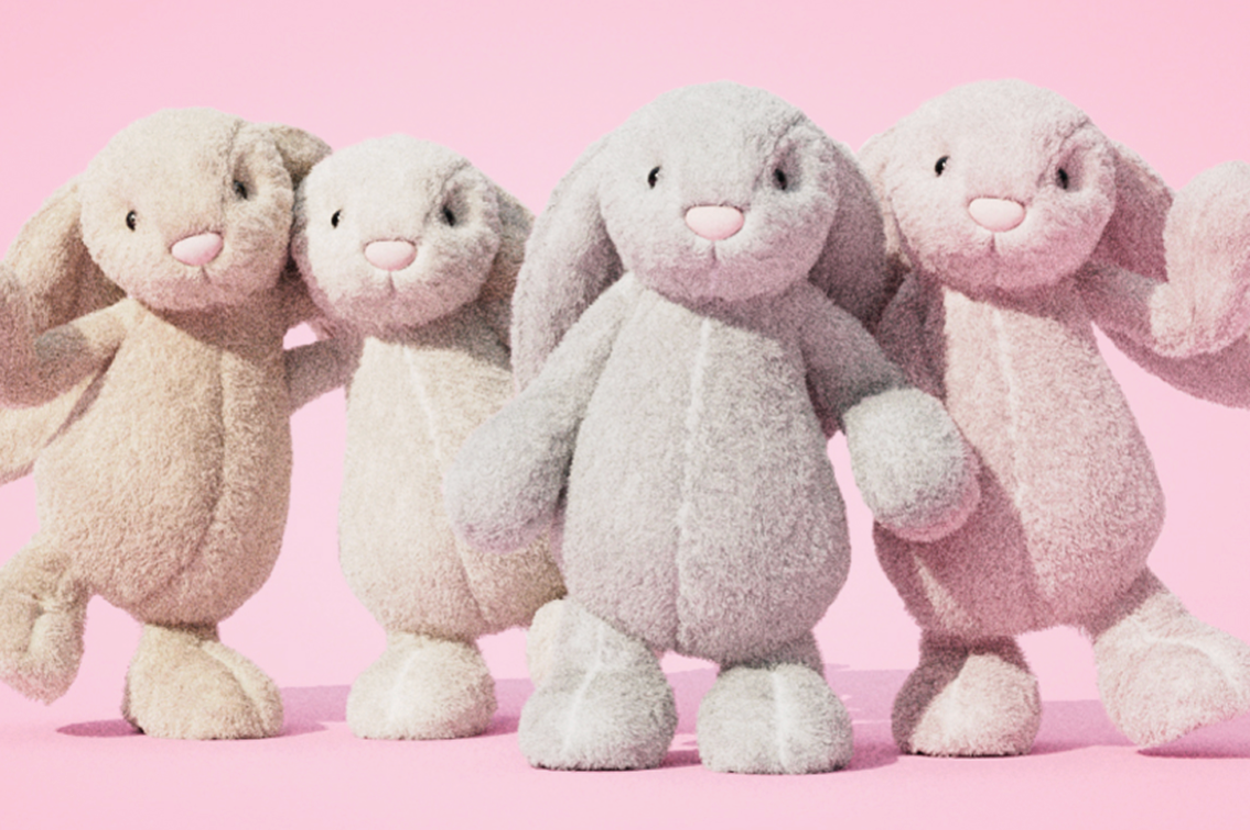 Four plush toy bunnies standing side by side, each with floppy ears and smiling faces