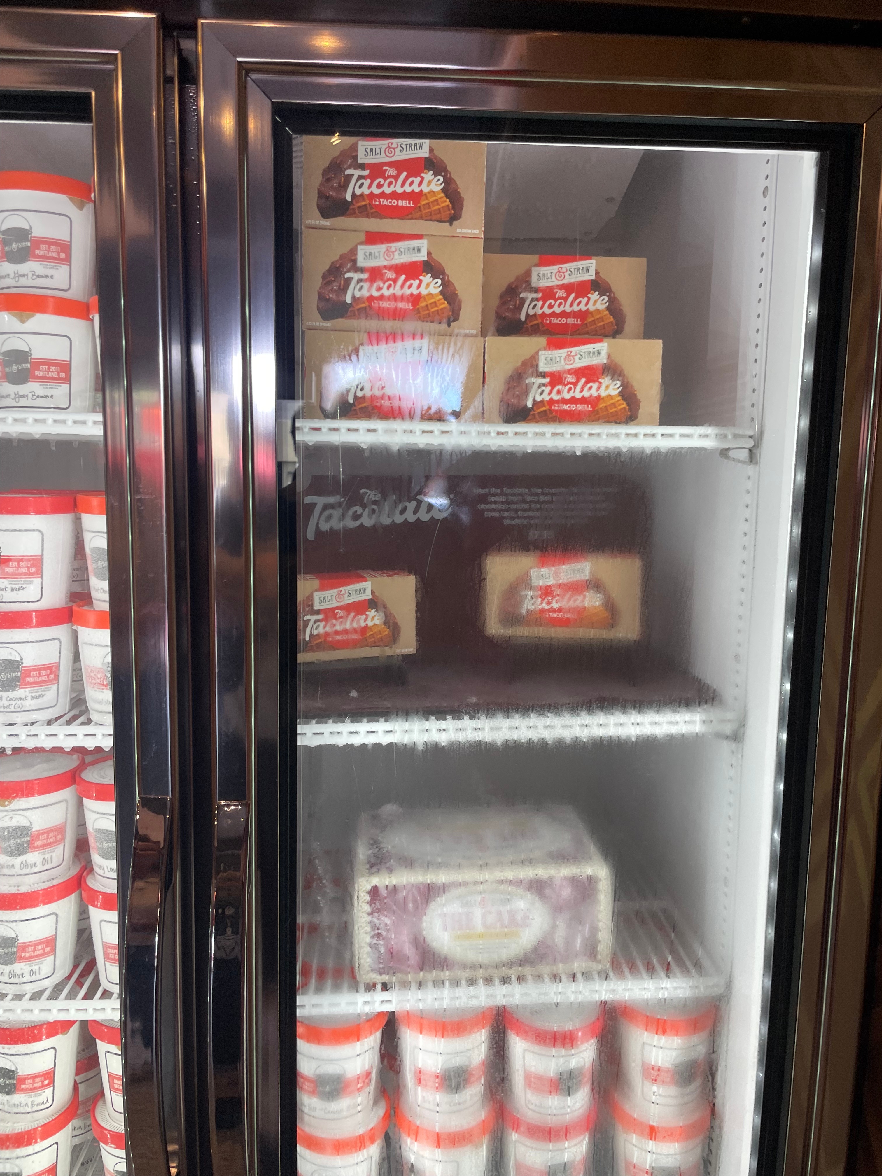Ice cream freezer with various tubs and Tacolate ice cream sandwiches displayed inside