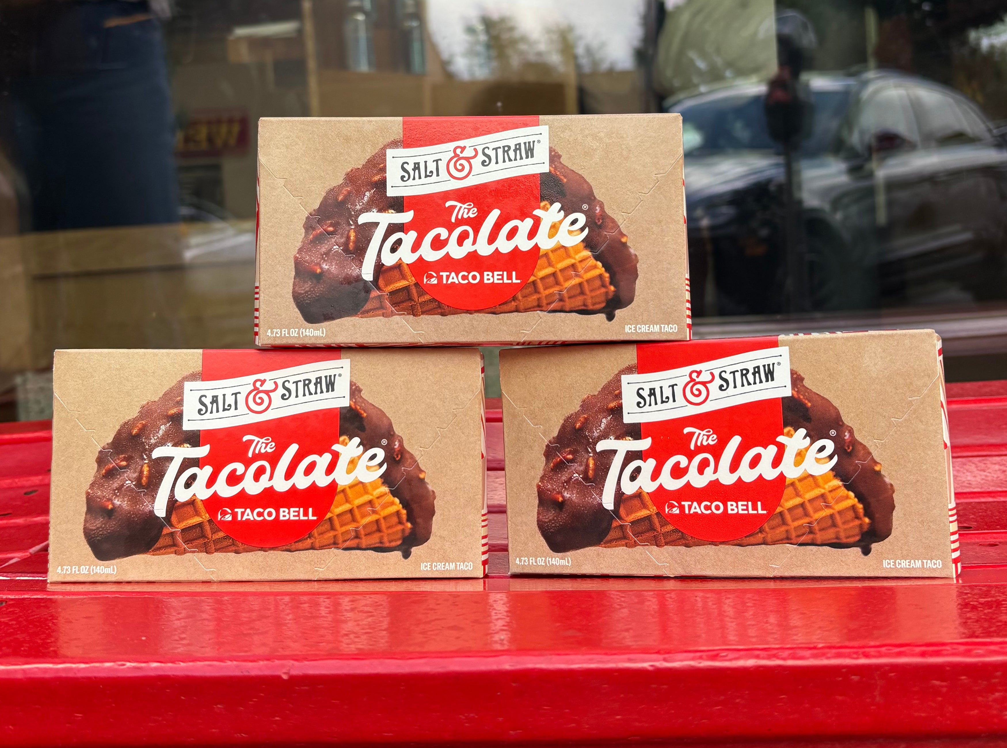 Three boxes of Salt & Straw's "The Tacolate" ice cream treat displayed on a red surface outside a shop