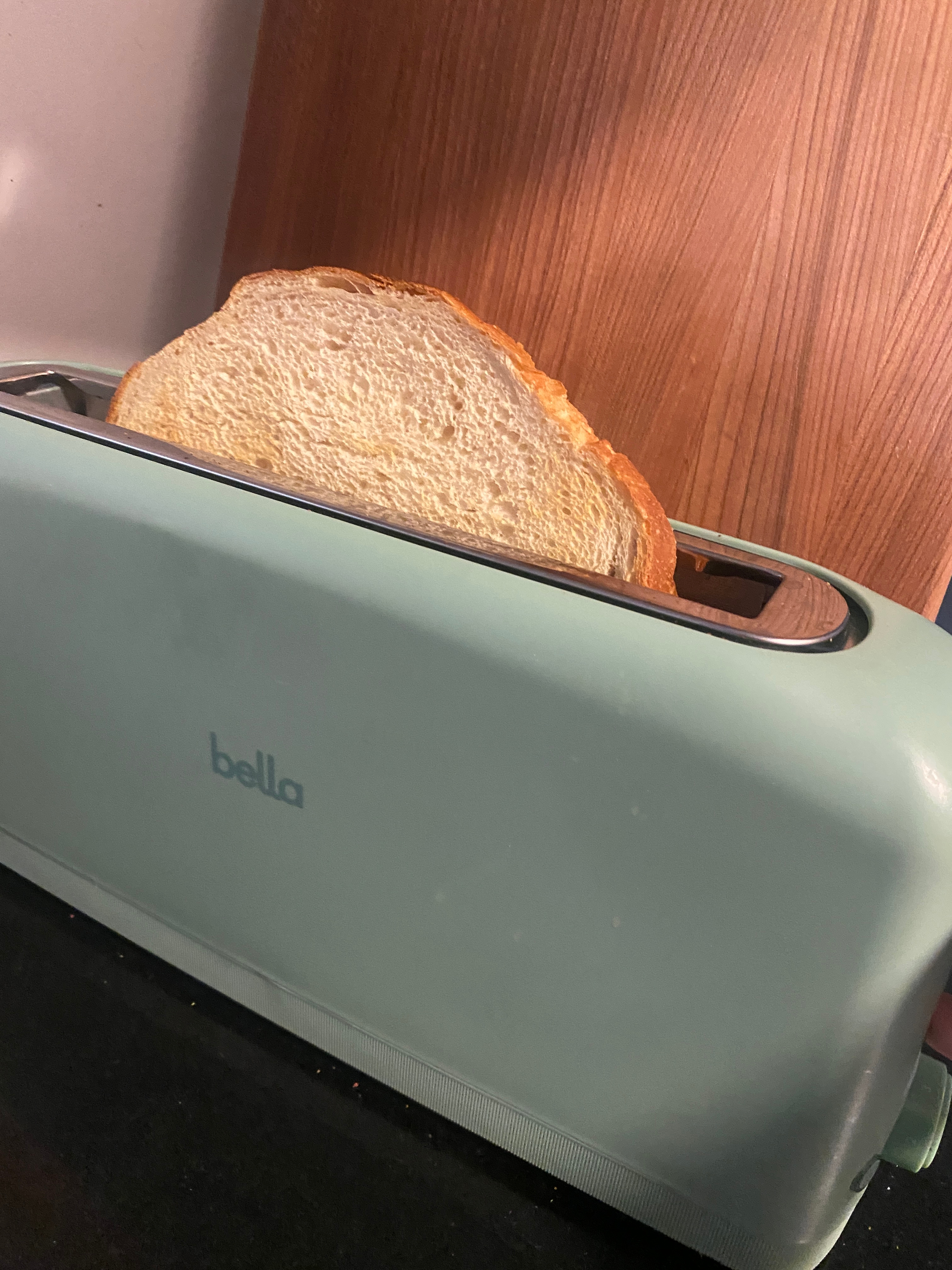 Slice of bread in a green toaster, ready to be toasted