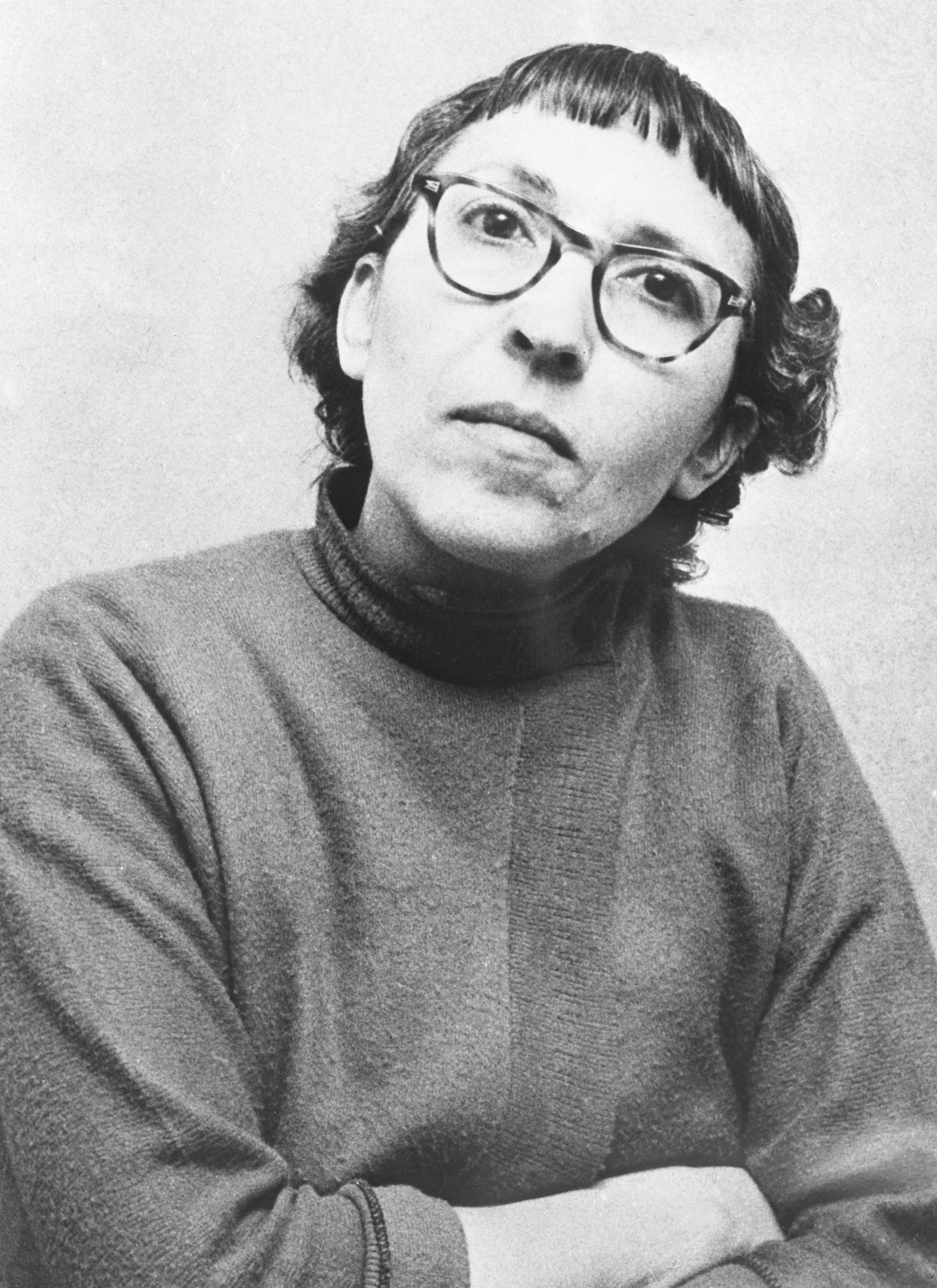 Person wearing glasses and a turtleneck, gazing upward thoughtfully