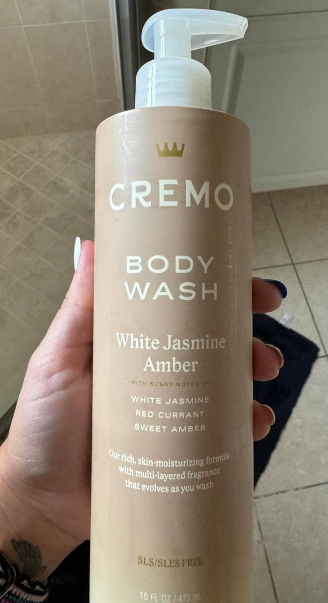 Cremo Body Wash bottle with a pump, labeled White Jasmine and Amber scent, featuring white jasmine, red currant, and sweet amber