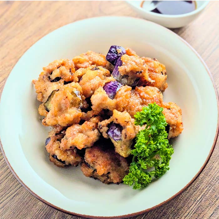 皿に盛られたなすと豚バラ肉の揚げ物とパセリ。背景にソース。