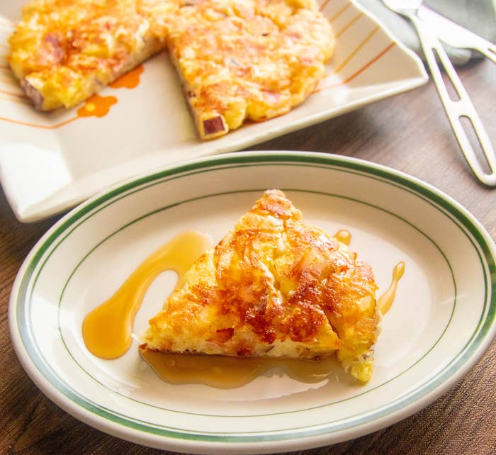 お皿に盛られたフレンチトースト風のパンケーキがシロップとともに置かれている。背景にもうひとつのパンケーキ。